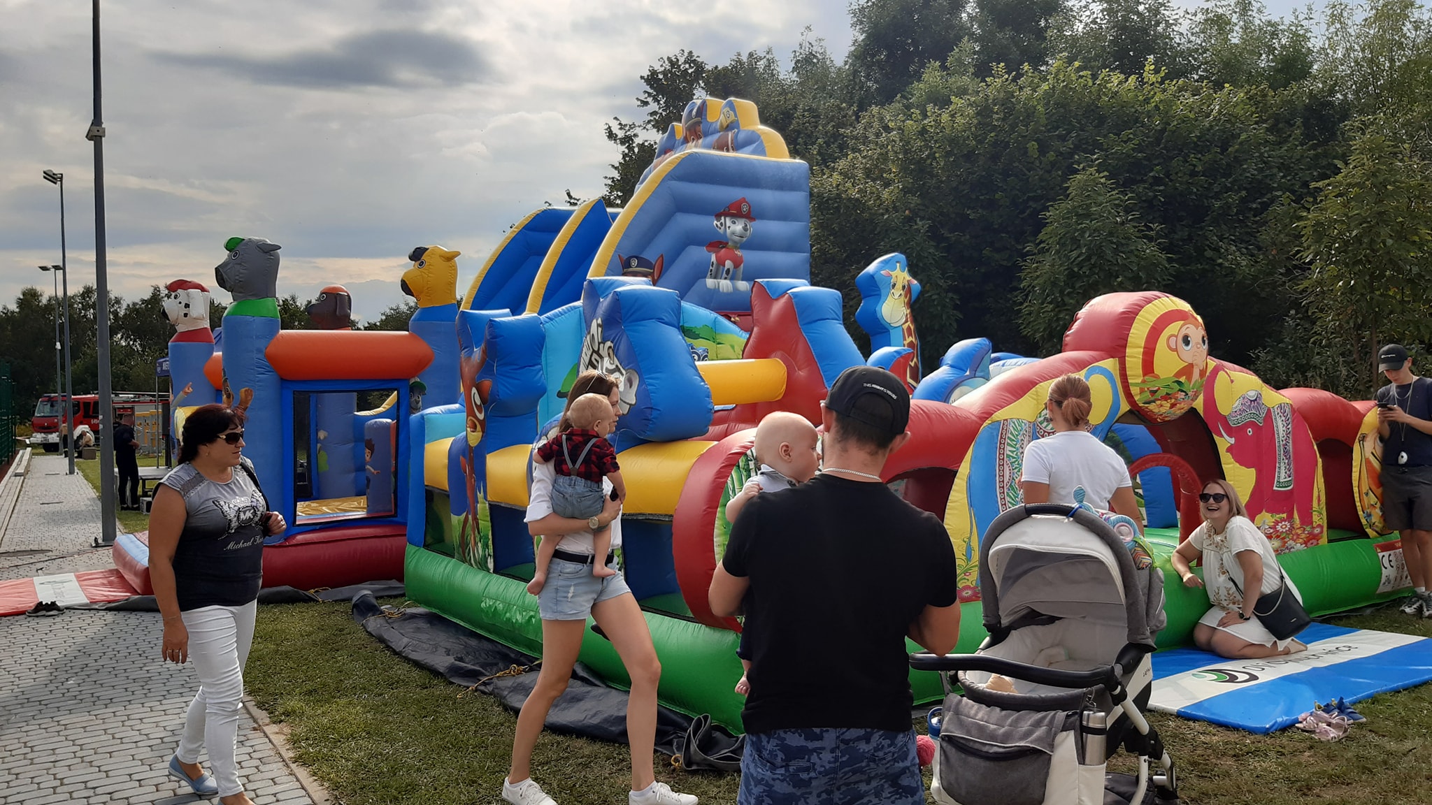 Rodzice z dziećmi w tle dmuchana zjeżdżalnia