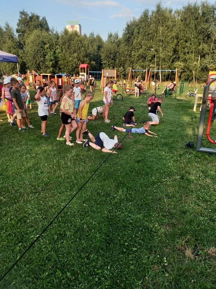 Dzieci uczestniczące w zabawie z animatorką - przechodzą pod liną 