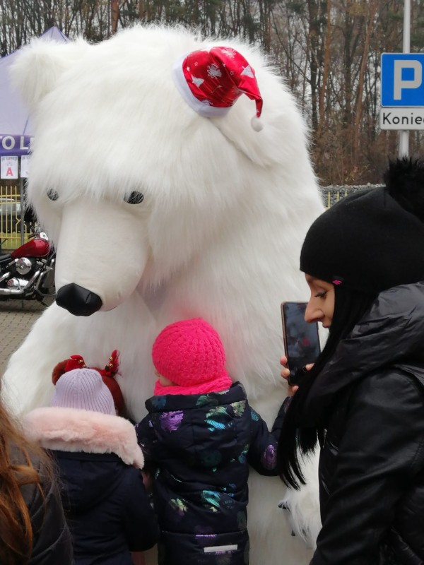 dzieci przytulają się do osoby przebranej za dużego białego misia