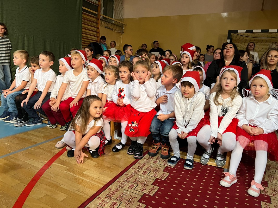 dzieci ubrane w czerwone czapki miłołajów. ubrane na biało i czerwono