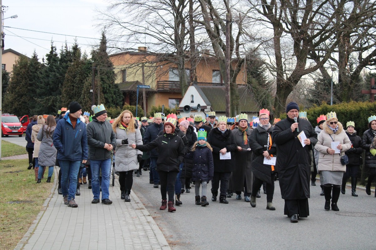 Ludzie w koronach na głowie idą ulicą podczas orszaku trzech Króli