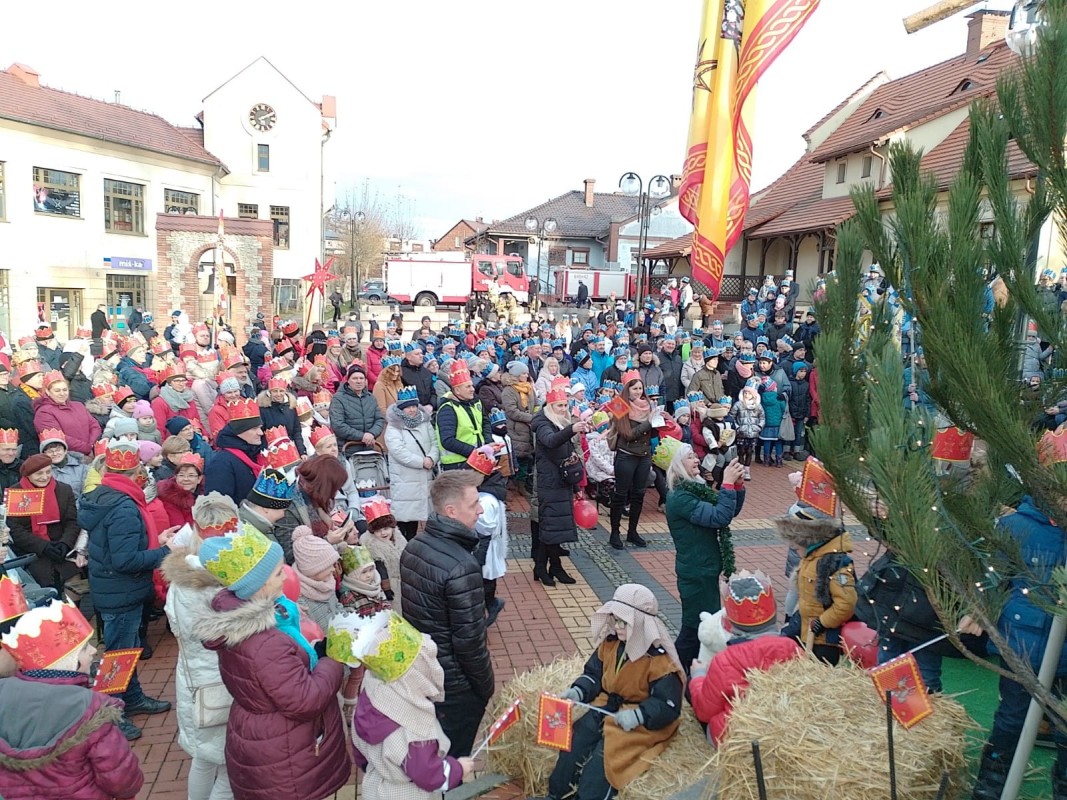 Ludzie w koronach na głowie podczas orszaku Trzech Króli. Stoją na placu Farskim w Lędzinach