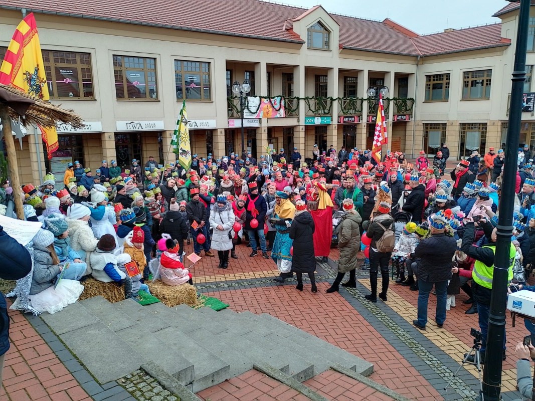 Ludzie w koronach na głowie podczas orszaku Trzech Króli. Stoją na placu Farskim w Lędzinach