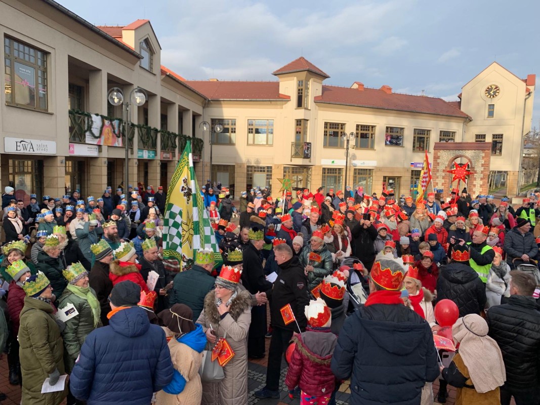 Ludzie w koronach na głowie podczas orszaku Trzech Króli. Stoją na placu Farskim w Lędzinach