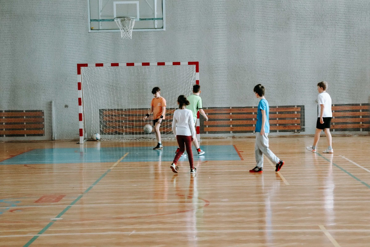 Dzieci grają w piłkę nożną na hali sportowej