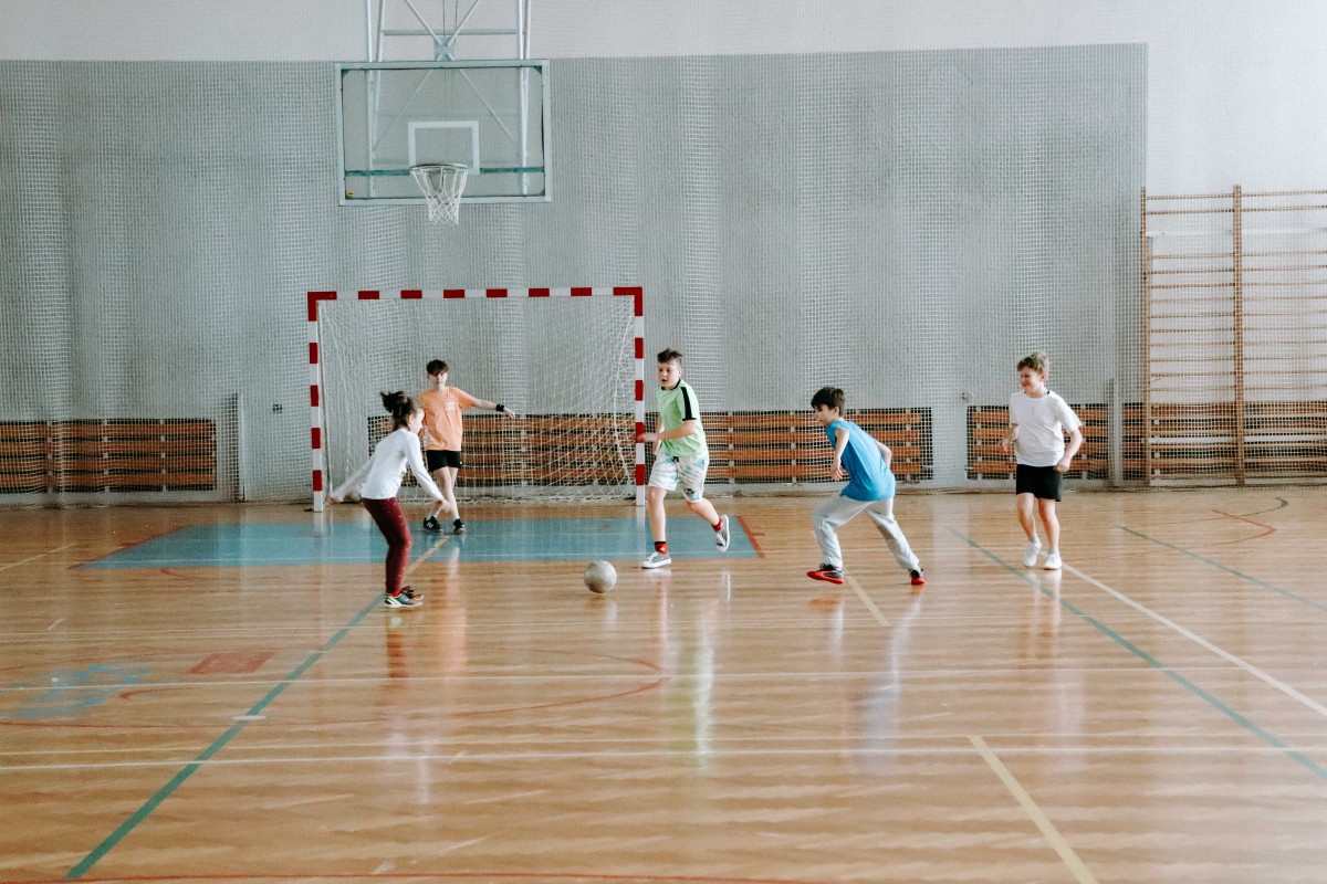 Dzieci grają w piłkę nożną na hali sportowej
