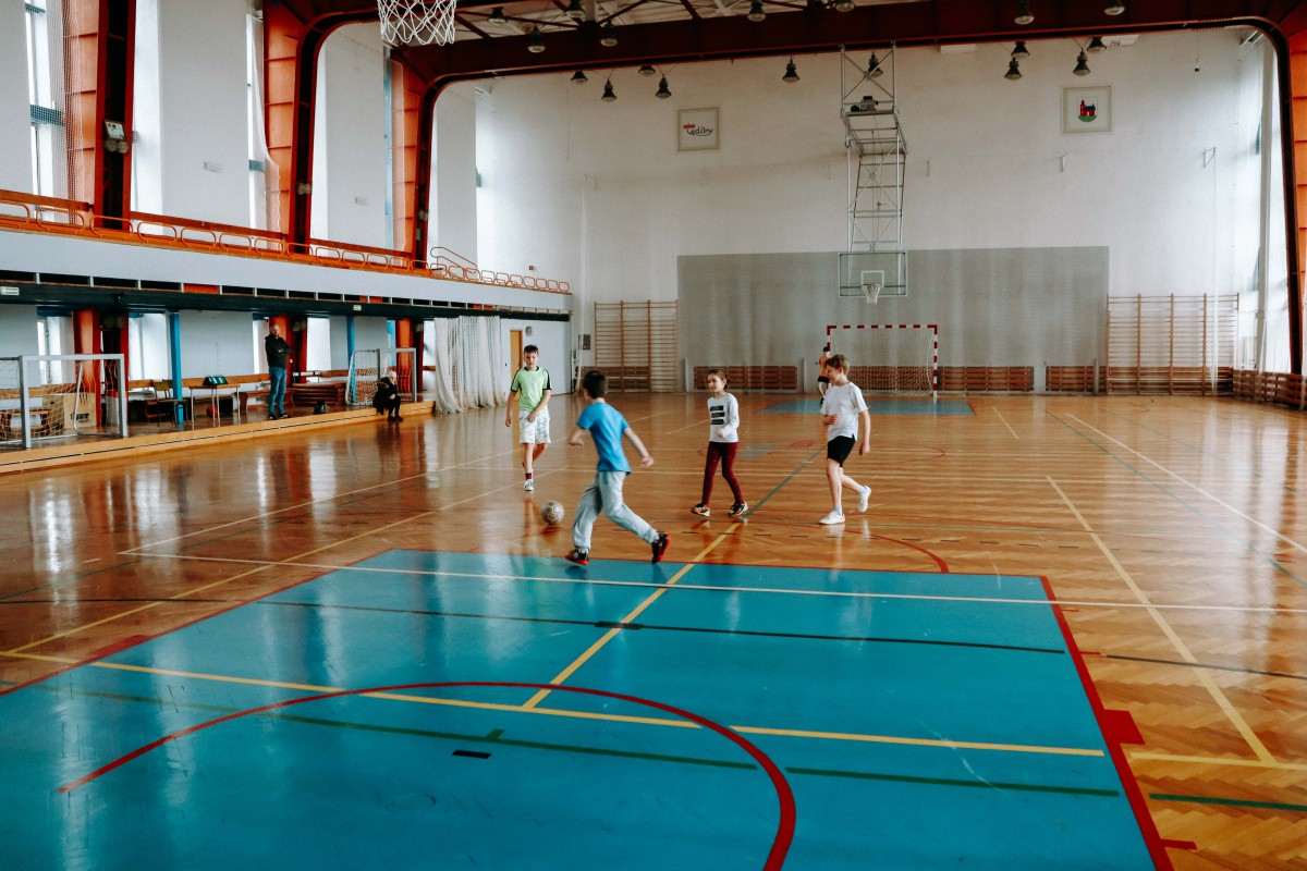 Dzieci grają w piłkę nożną na hali sportowej